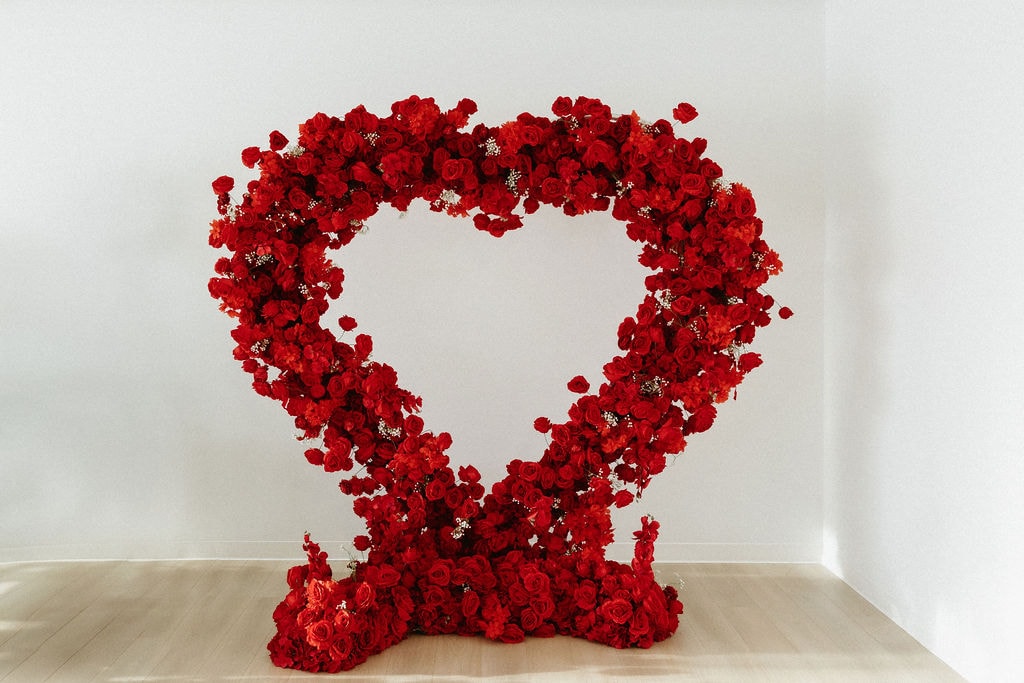 Elegant heart-shaped floral display made with vibrant red roses, perfect for romantic occasions and weddings.