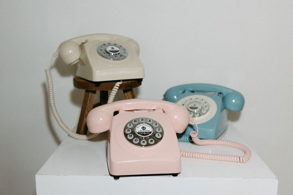 Colorful vintage rotary phones in pink, blue, and beige for retro-themed event decoration.